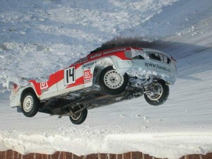 A car is lying on its roof in the snow, but the photo is upside down giving an irregular perspective.