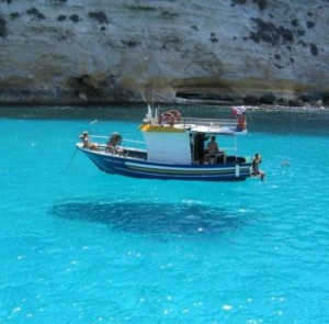A boat is sailing on beautiful clear blue water giving the impression it is floating above the water.