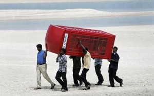 Some men are carefully carrying a red English telephone box.