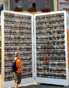 some or any in questions A man is standing next to a giant fridge containing some beer.